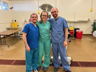 Three people in scrubs pose in a laboratory setting